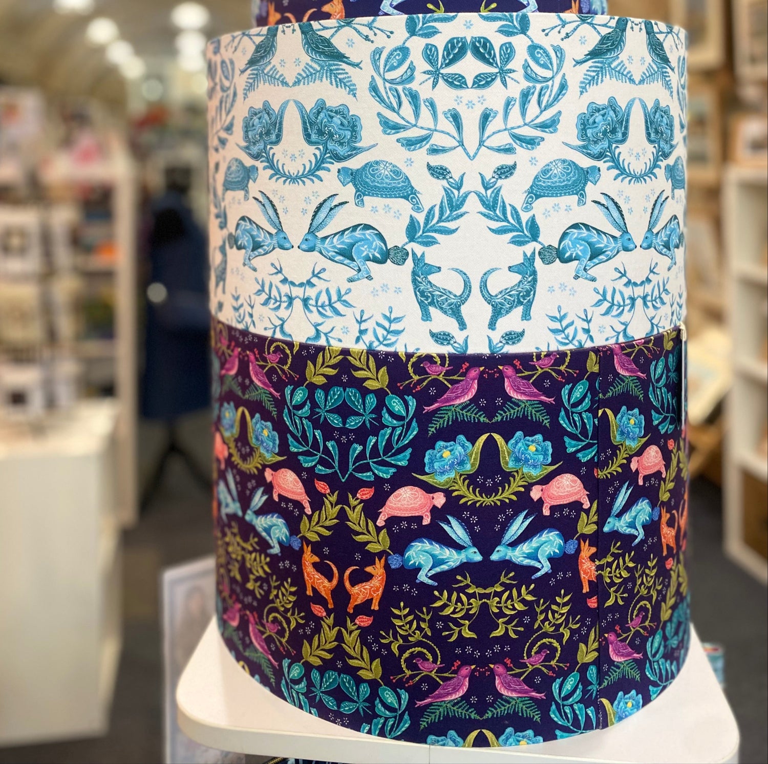 Two drum lampshades with Belle Design Original Hare and Tortoise patterns in a shop.