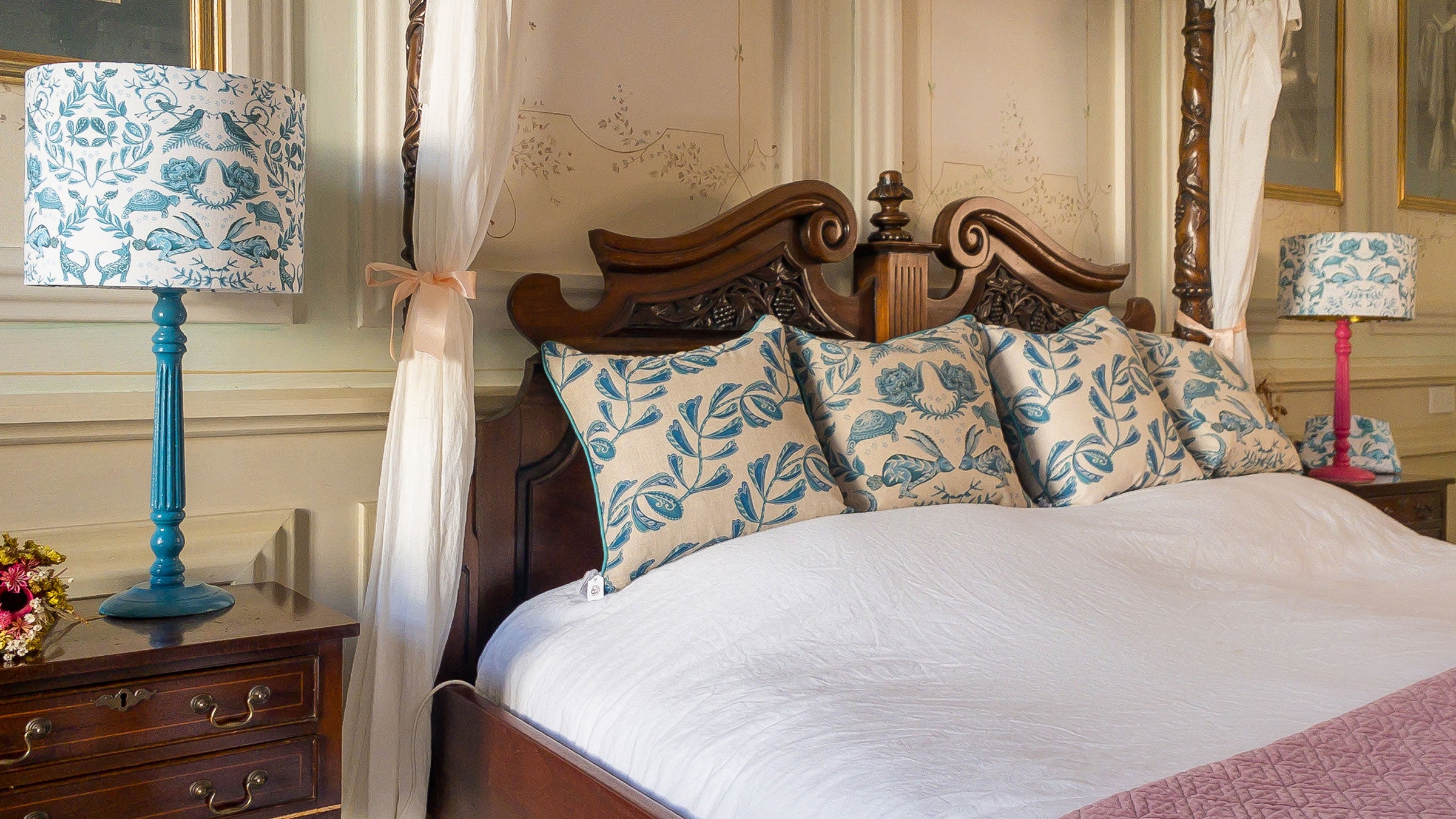 Decorative bedroom with a canopy bed, floral lamps, and matching pillows.